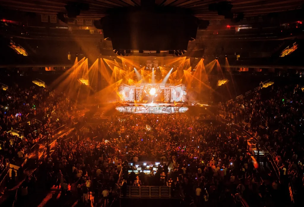 Concert venue filled with audience and vibrant stage lighting, showcasing audio and visual presentation excellence.