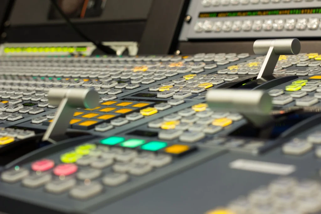 Close-up of a video production switcher with numerous buttons and levers.