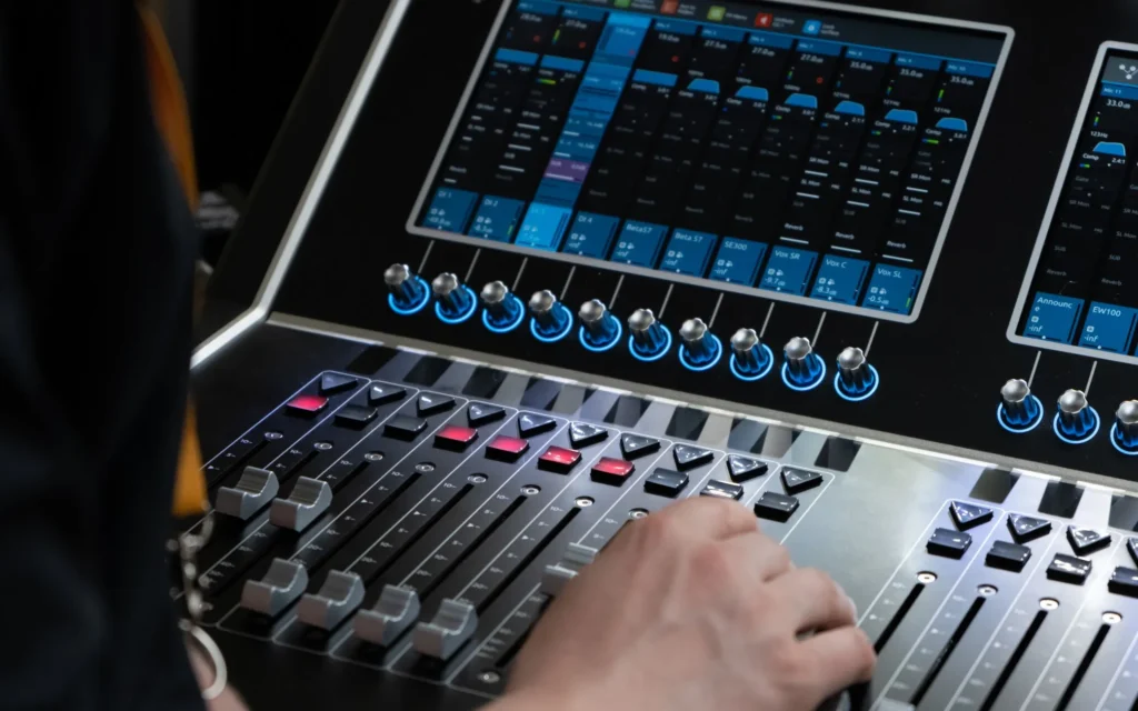 Person adjusting controls on a mixing console with a digital display.