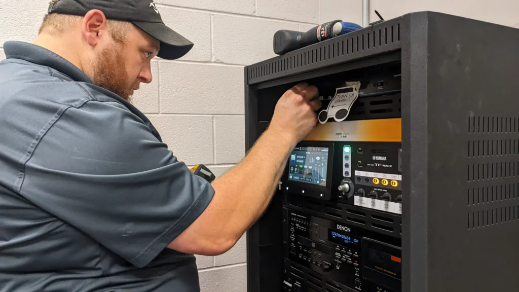 Man adjusting audio equipment in a server rack.
