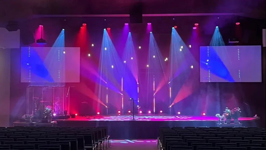 Stage with colorful lighting, spotlights, and empty seating.