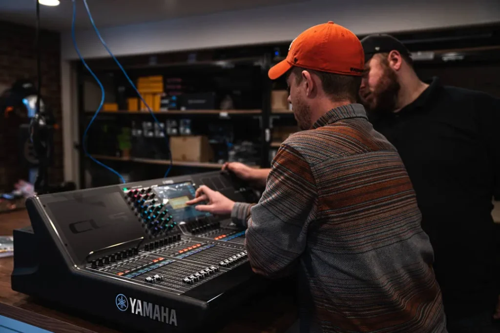 Technicians adjusting audio settings on a sound mixing console.
